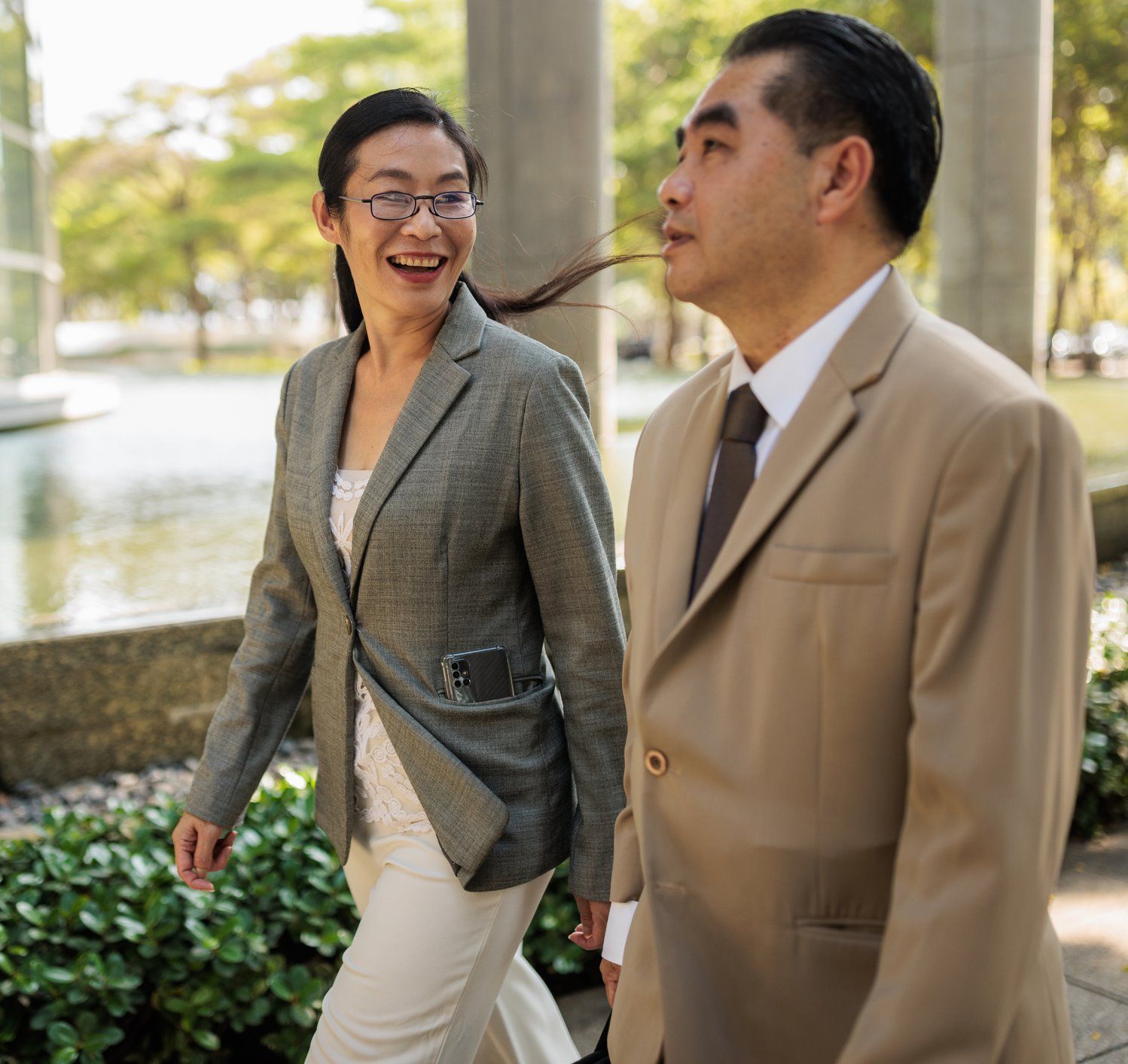 Colleagues walk outside. The person on the left is smiling and listening to their coworker. 